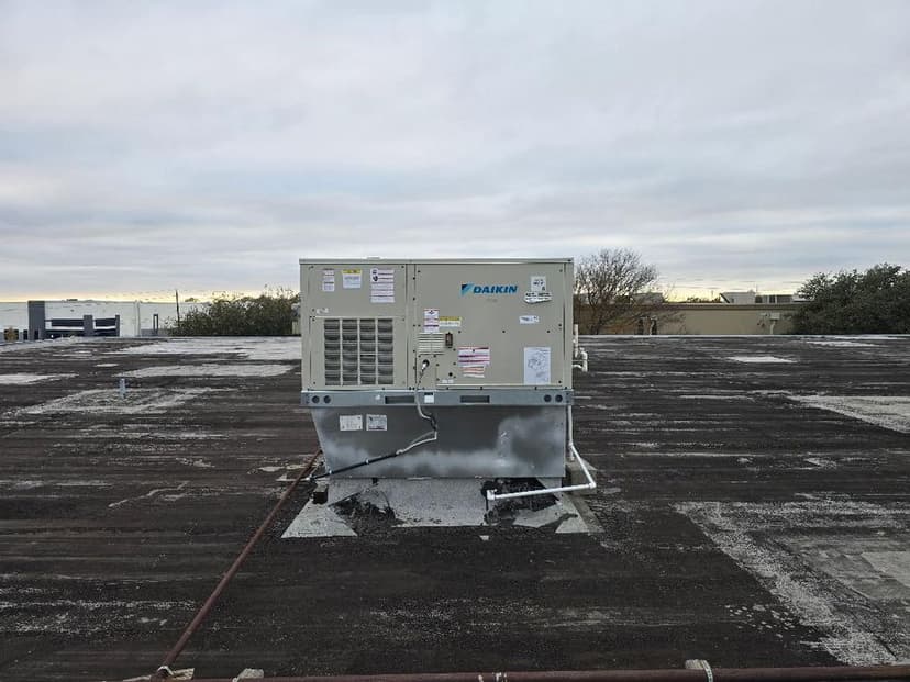 Daikin HVAC unit on a commercial roof with overcast sky in the background.